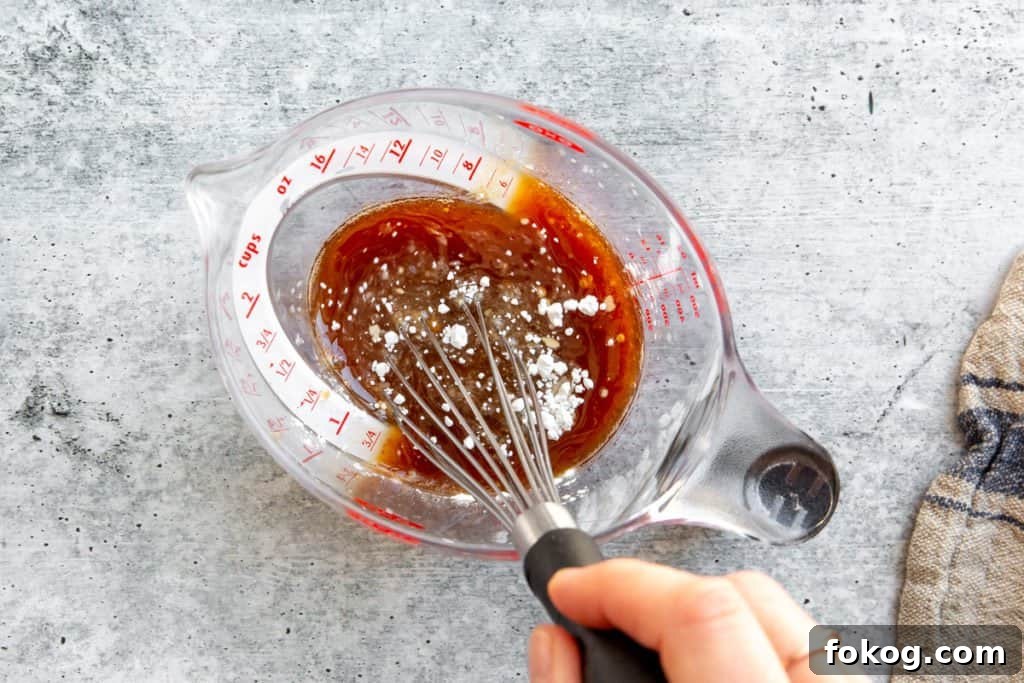 Process shot showing a hand whisking together the sauce for the beef lettuce wraps recipe.