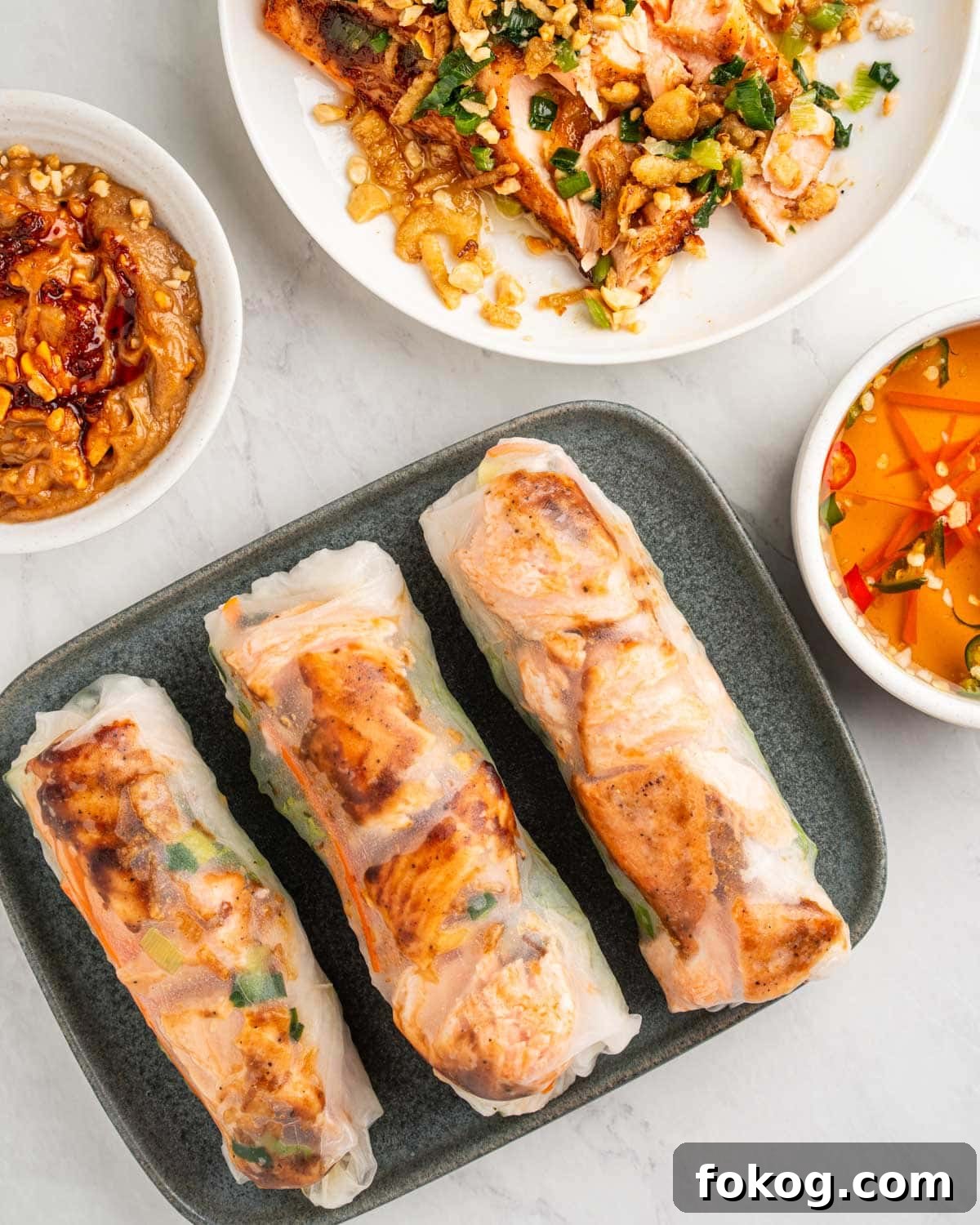 plate of salmon spring roll with peanut sauce and fish sauce.