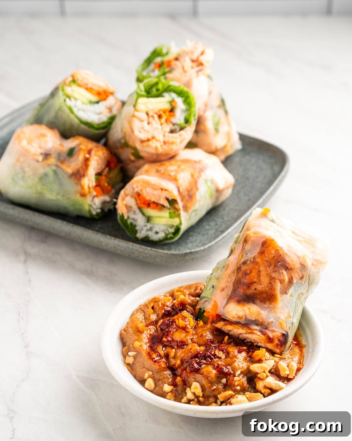 salmon spring roll dipping into peanut sauce.
