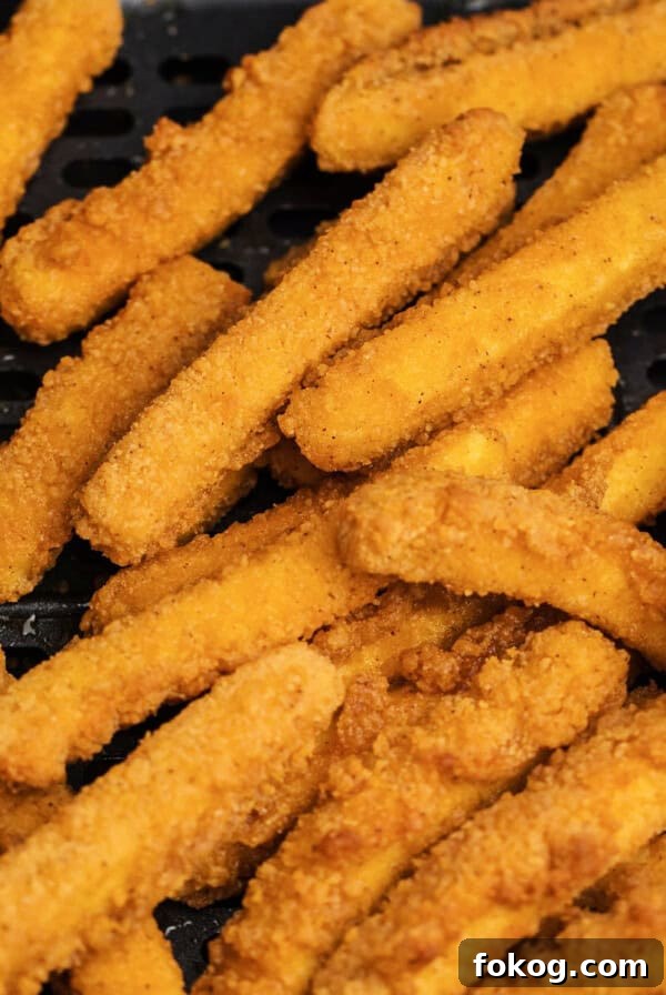Cooked chicken fries in air fryer basket.