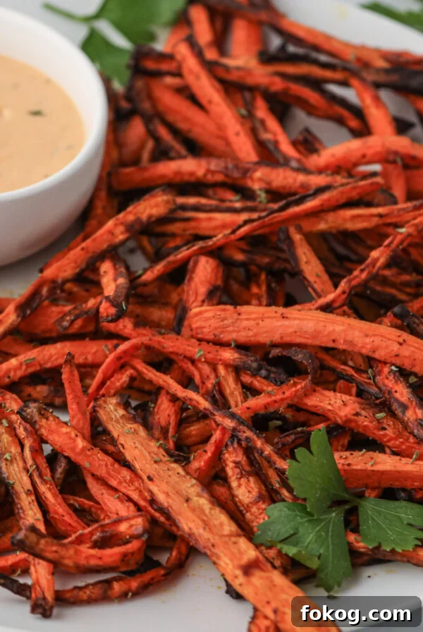 Carrot fries made in the air fryer and served on a plate with dipping sauce.