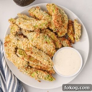 Overhead photo of air fried avocado fries on a white plate with dipping sauce.