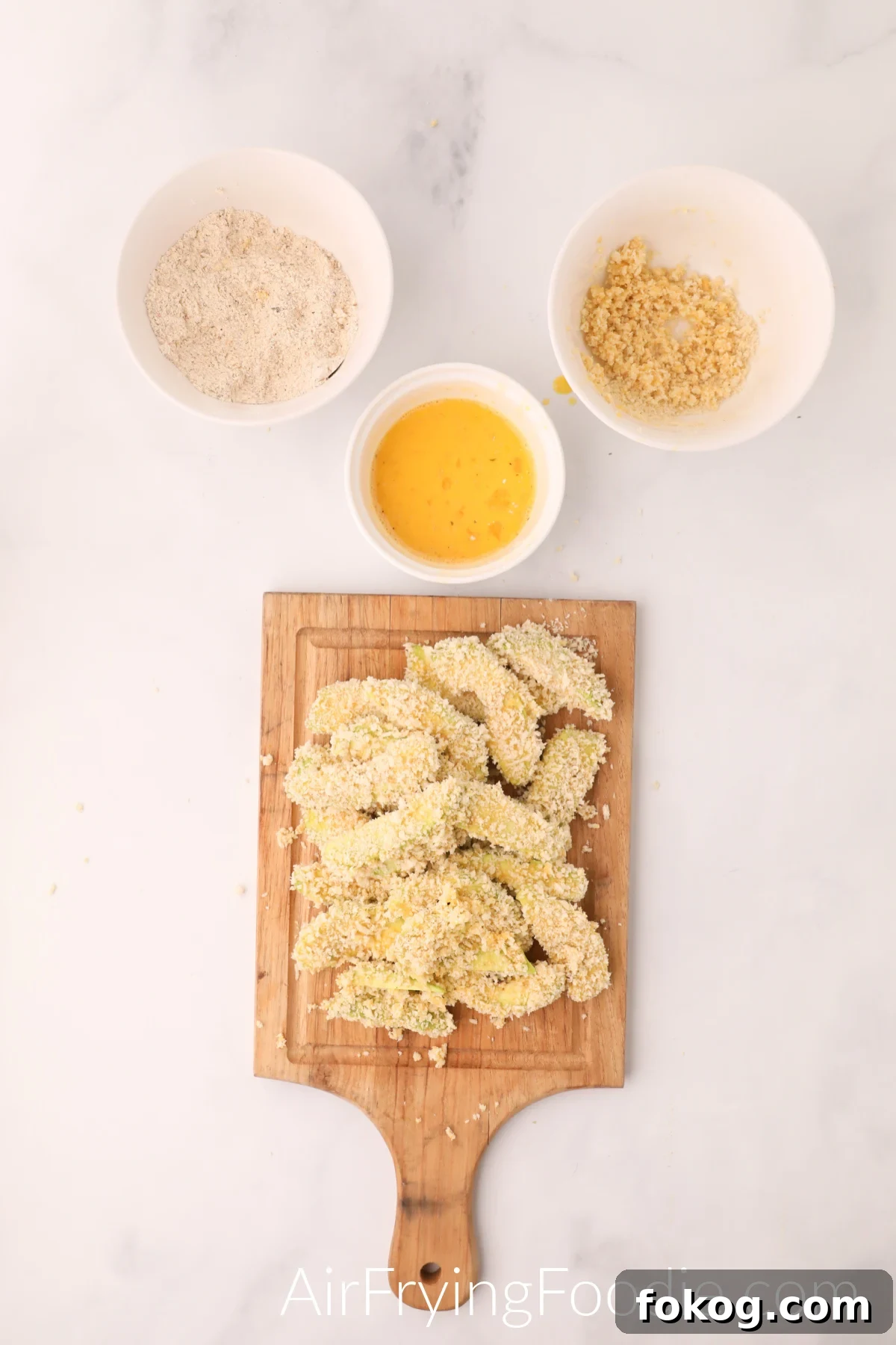 Avocado fries dipped into breadcrumb and egg mixtures before cooking.