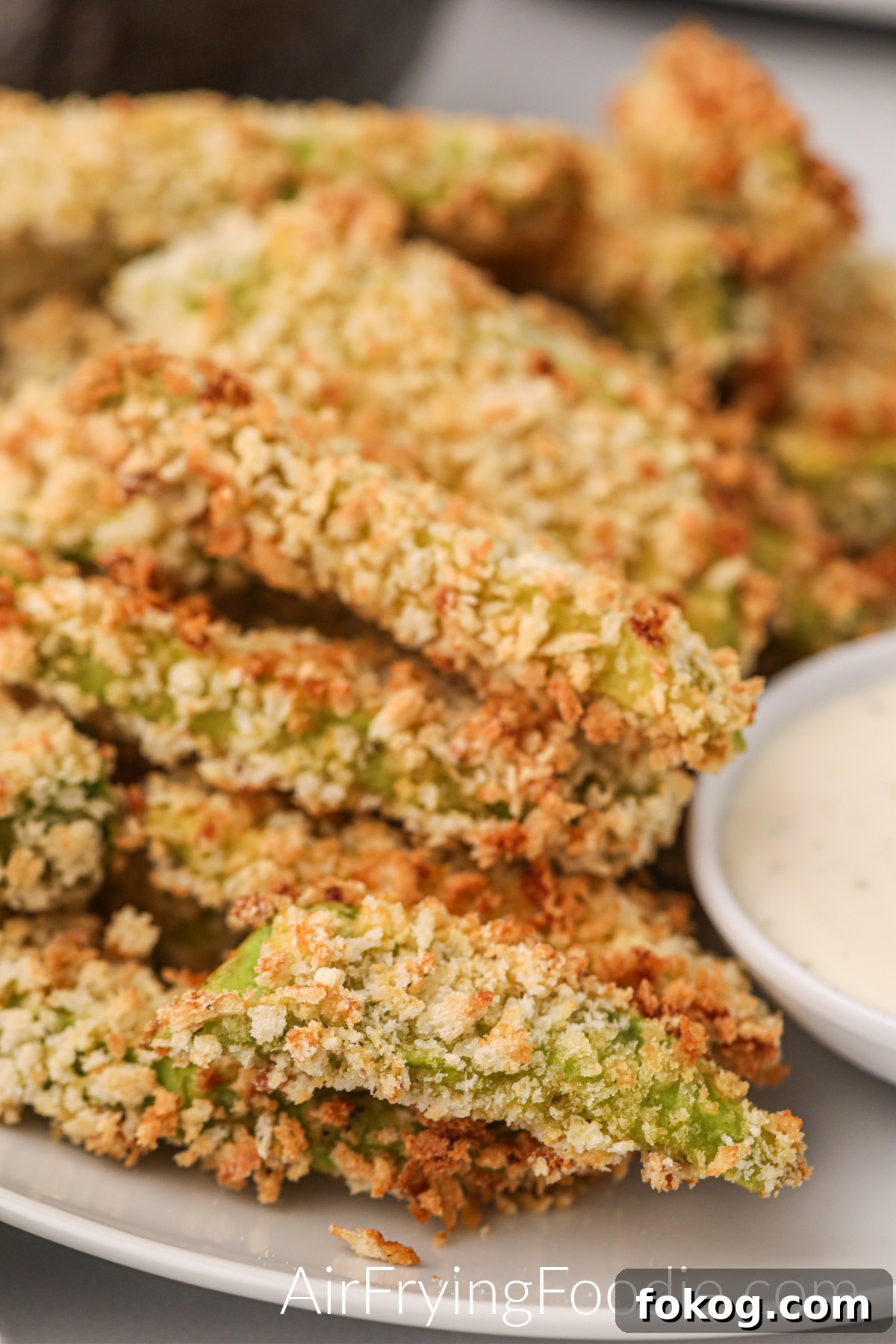 Avocado fries made in the air fryer and served on a white plate.