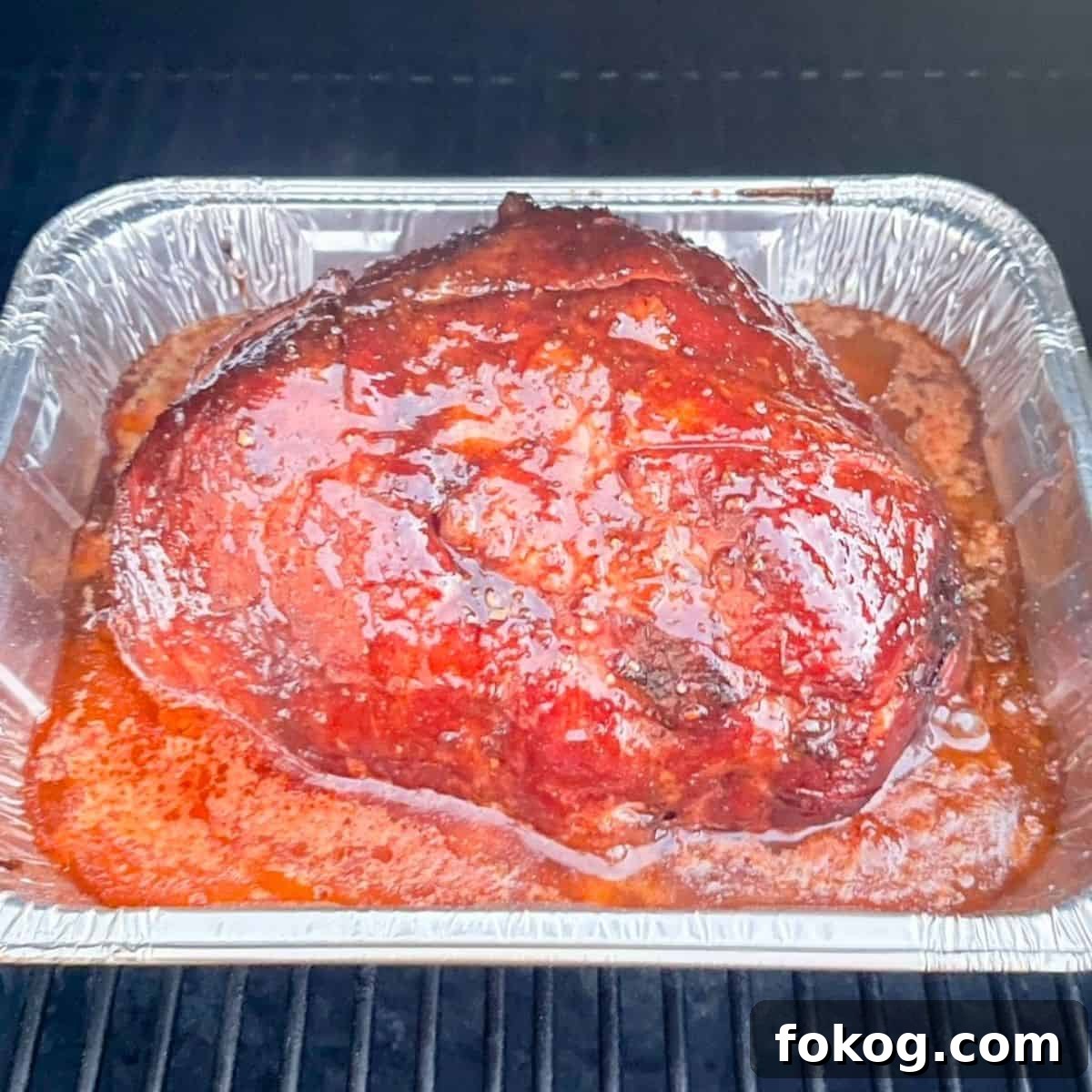 The ham on the pellet grill with the glaze applied.