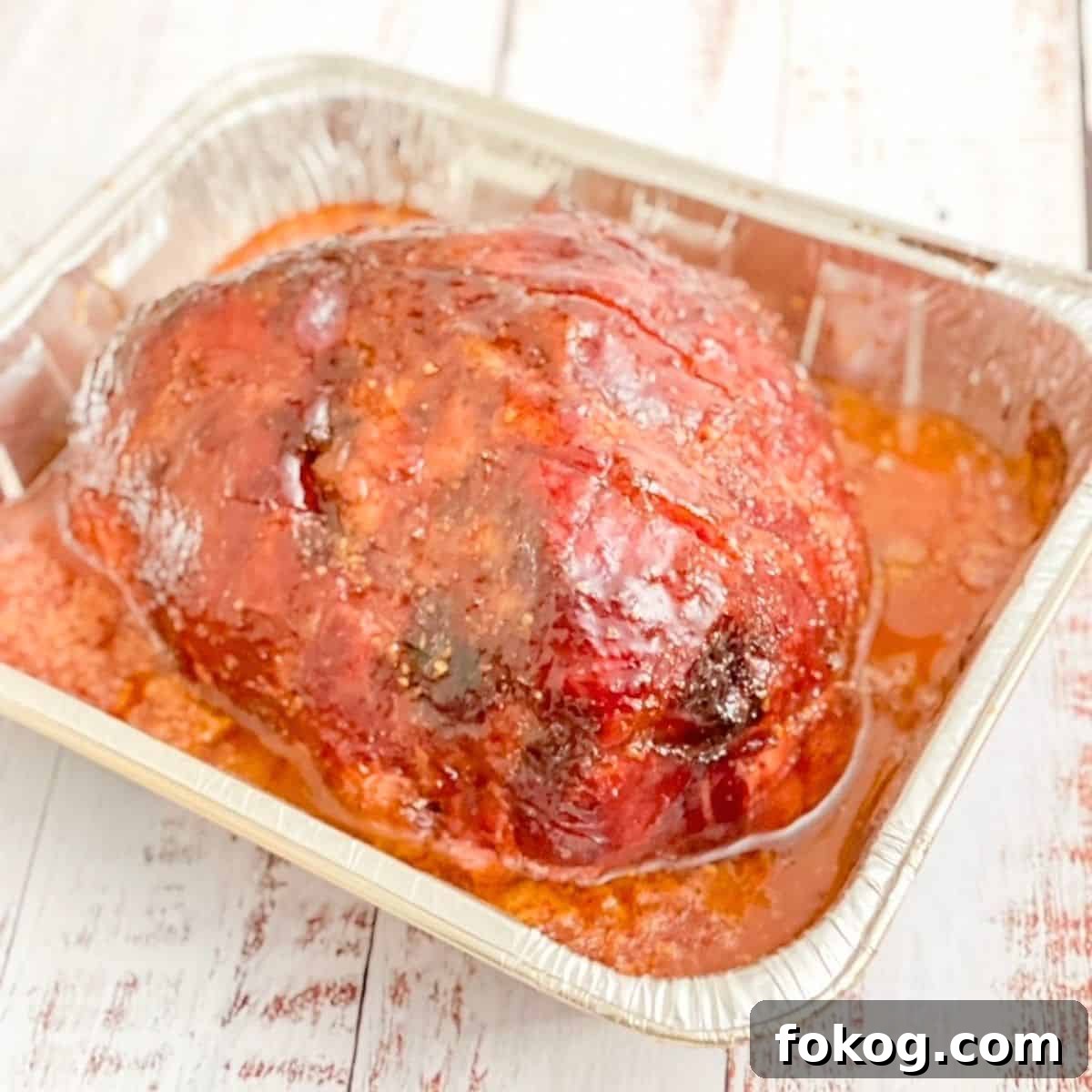 The double smoked ham brought inside from the pellet grill, placed on a white table.