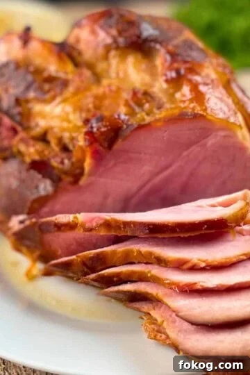 A fully cooked ham on a serving platter with thin slices.