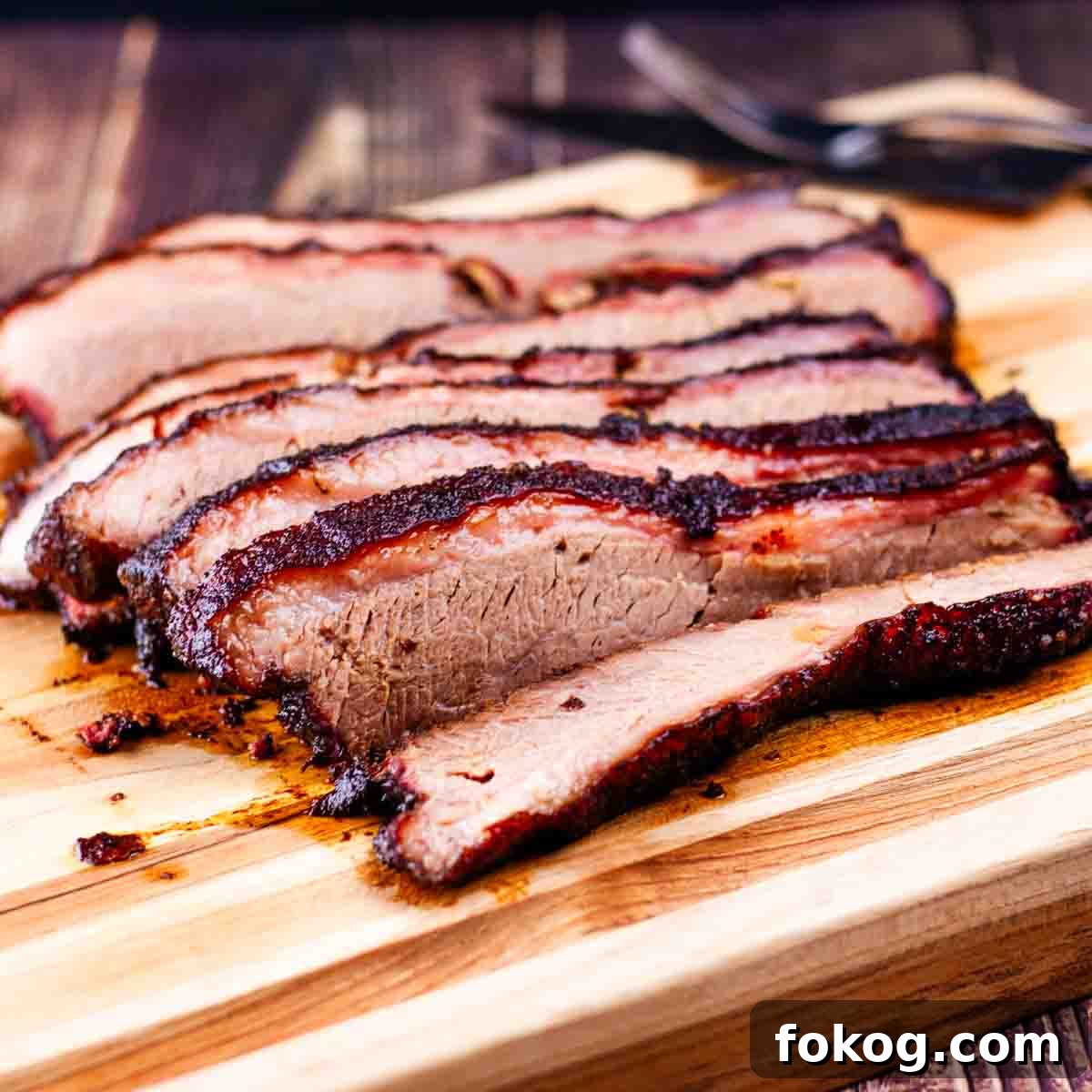 The juicy brisket cut into thin slices on a wooden cutting board.