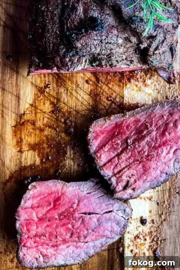Smoked beef tenderloin sliced into two steaks on a wooden cutting board.
