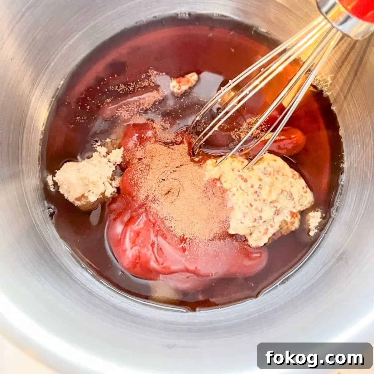 A whisk mixing together the ingredients for the brown sugar maple glaze in a small saucepan.