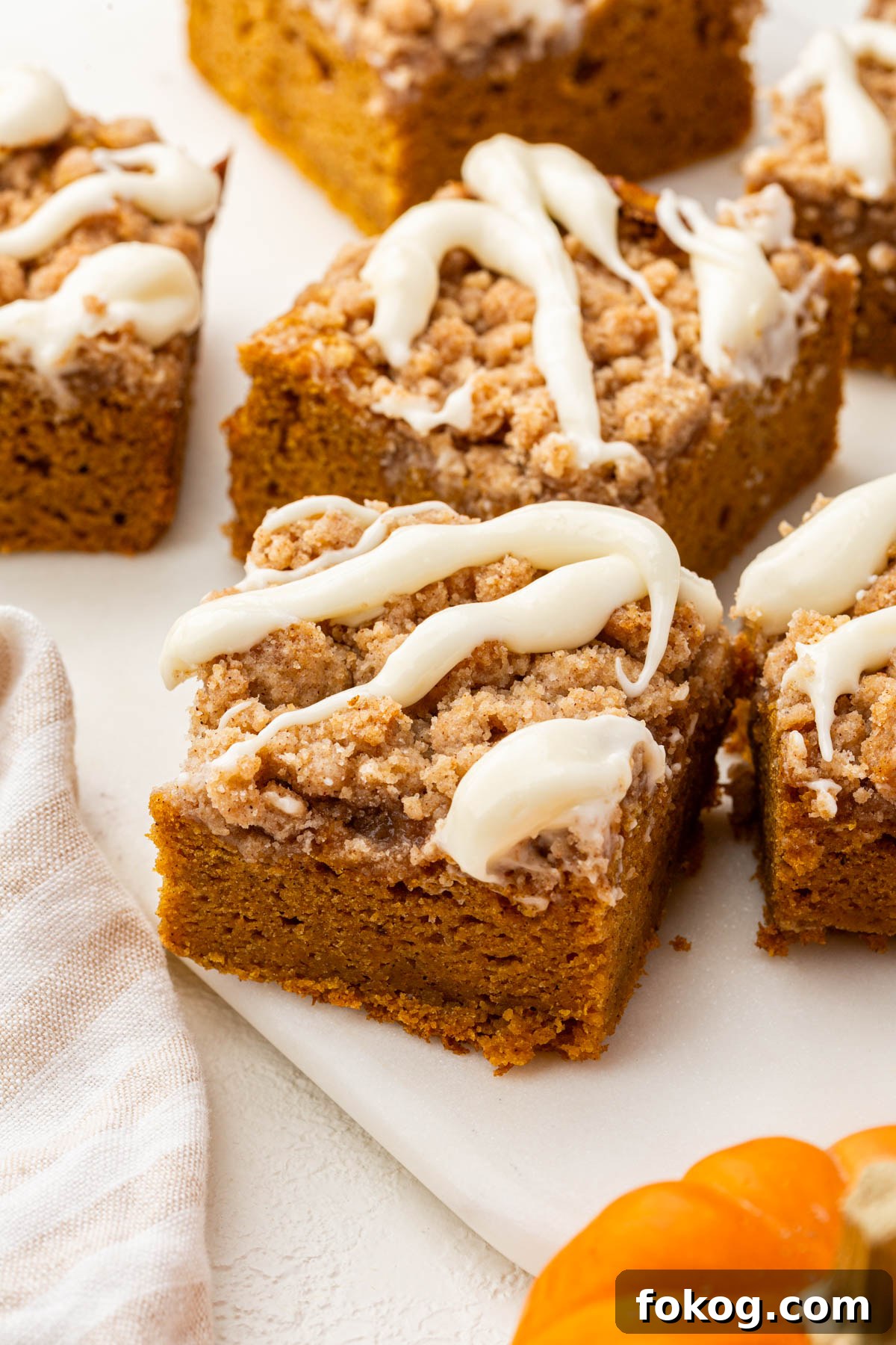 Hero image of a thick, golden slice of gluten-free pumpkin coffee cake with creamy glaze and crumb topping.