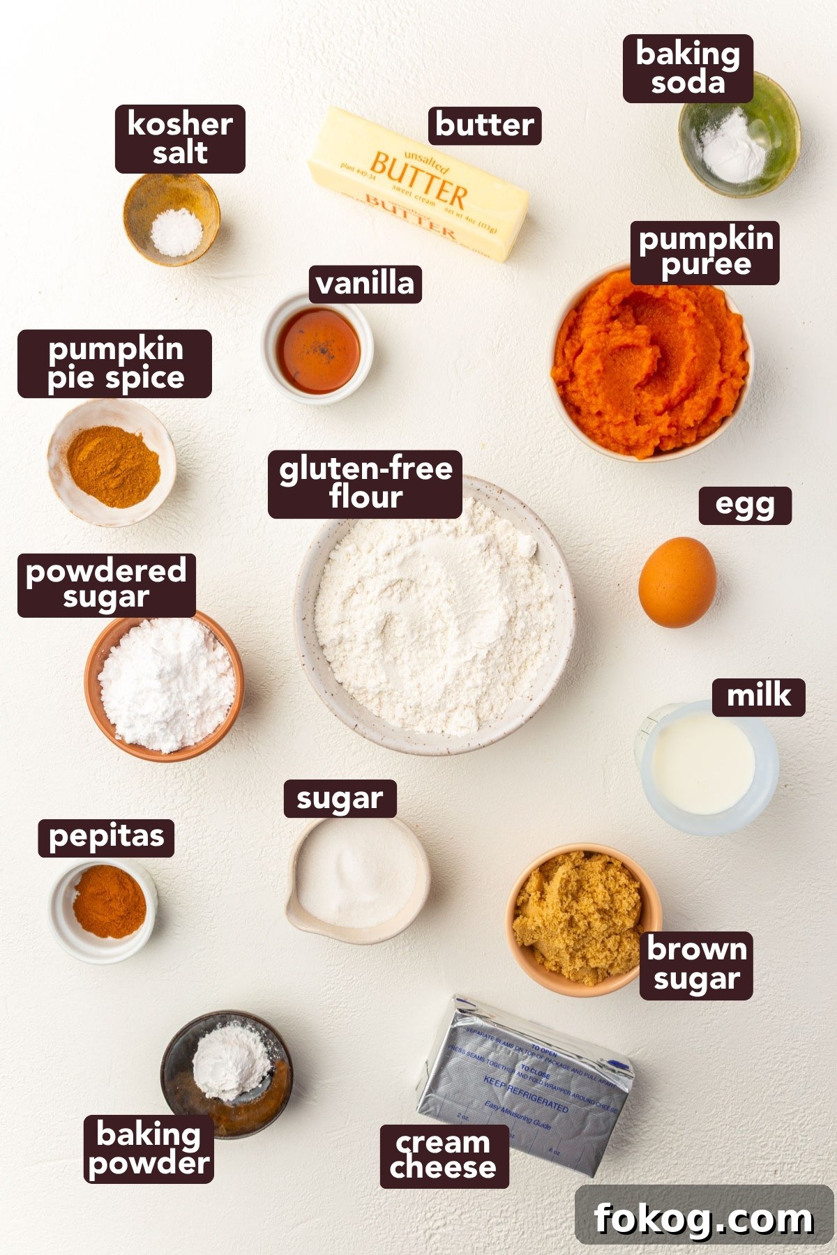 Overhead view of labeled ingredients for gluten-free pumpkin coffee cake including pumpkin purée, gluten-free flour, brown sugar, and cream cheese.