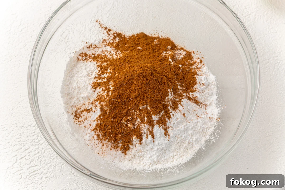 Gluten-free flour, baking powder, baking soda, salt, pumpkin pie spice in a large glass mixing bowl.