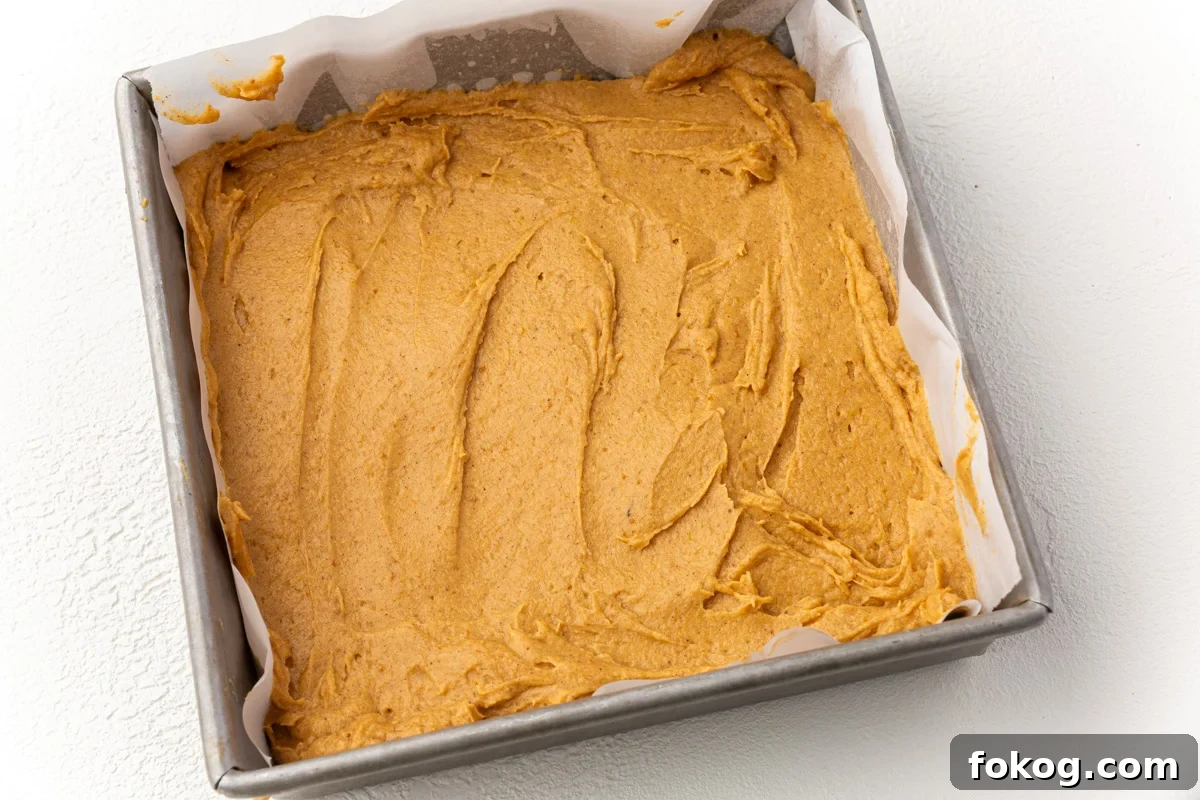 Evenly smoothed pumpkin coffee cake batter in baking pan ready for streusel topping.