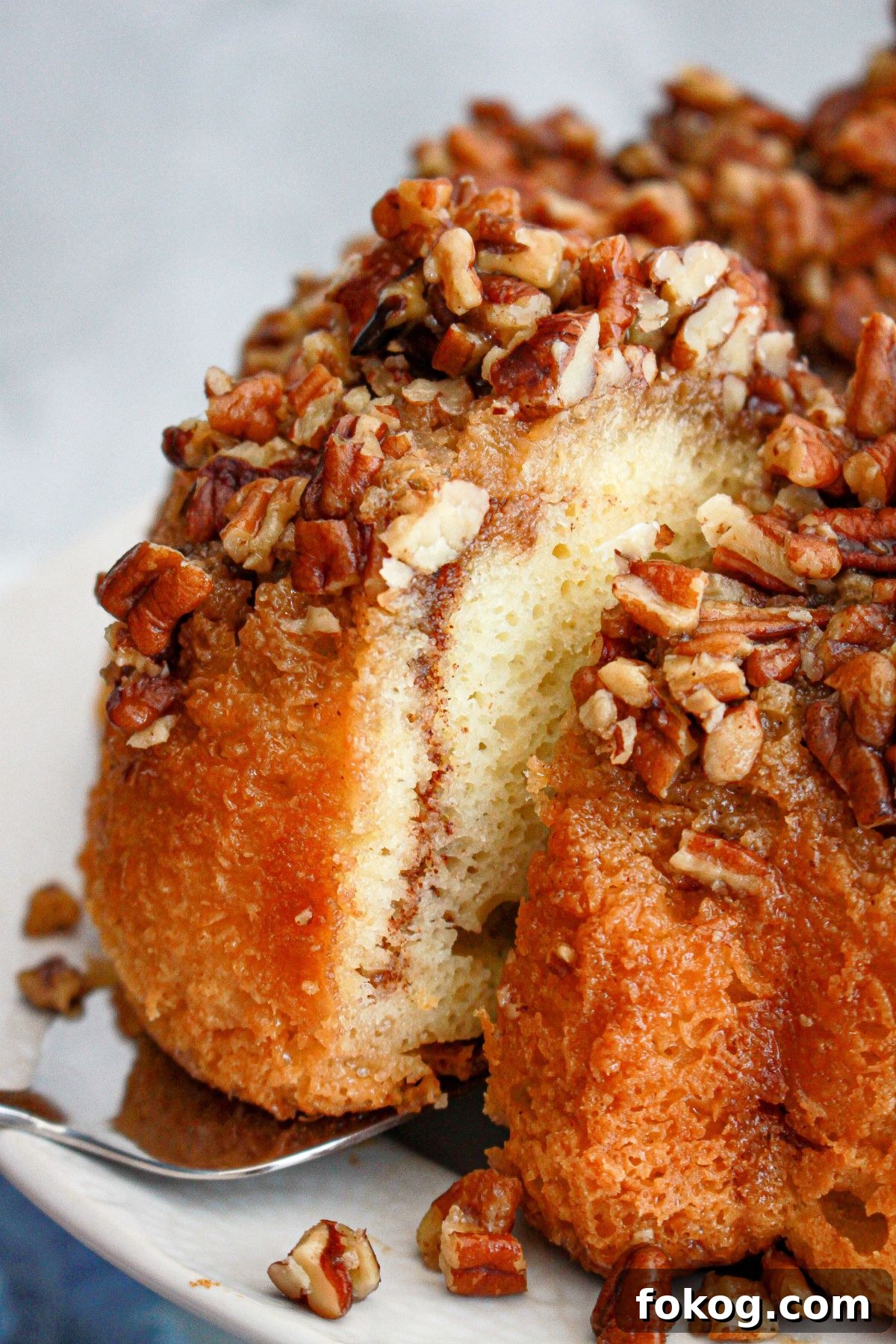slice of pecan upside down cake being removed from the pan.