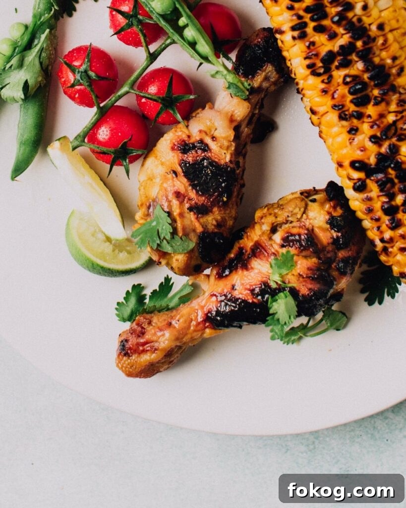 41 Juicy Chicken Drumstick Recipes You’ll Want Tonight 5 Garlic & Lime Grilled Chicken on a plate with corn cob, baby tomatoes and sliced lime wedges
