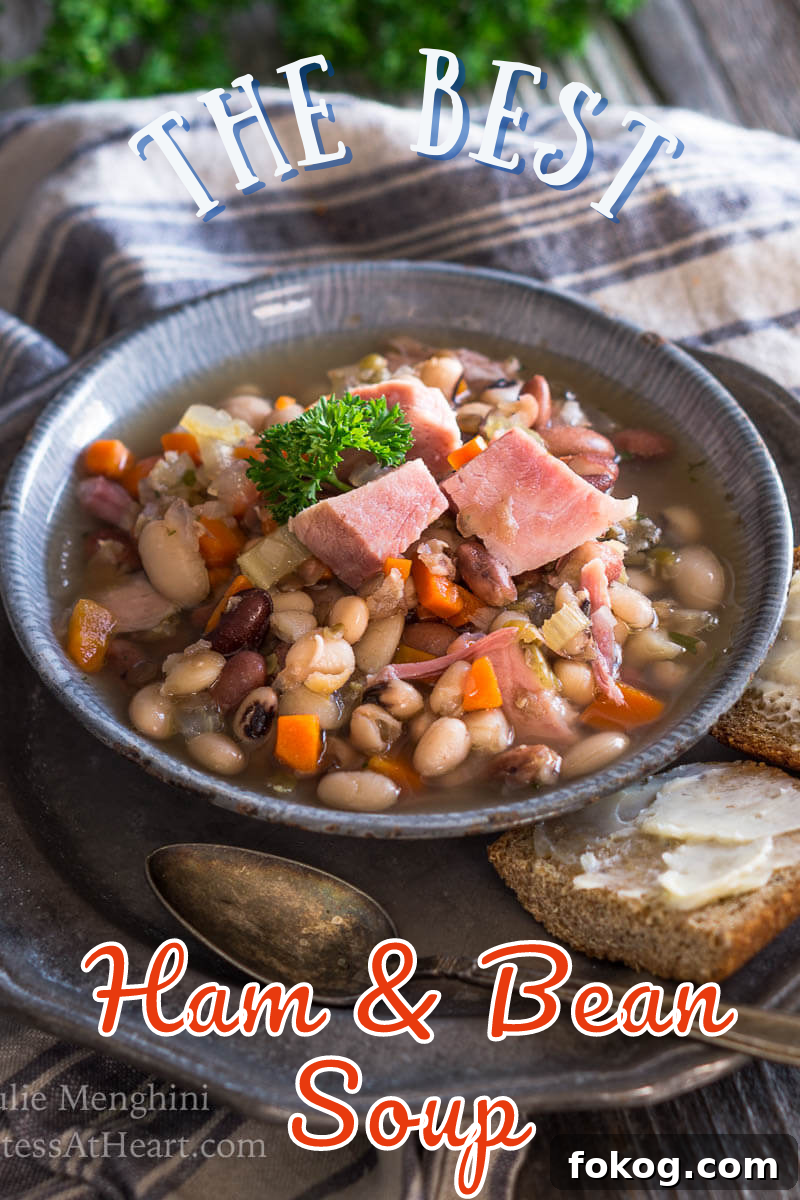 3/4 view of a bowl of soup filled with ham, beans, and carrots.