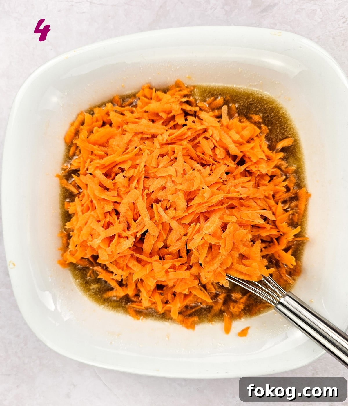 Grated carrot in carrot cake recipe batter in a mixing bowl.