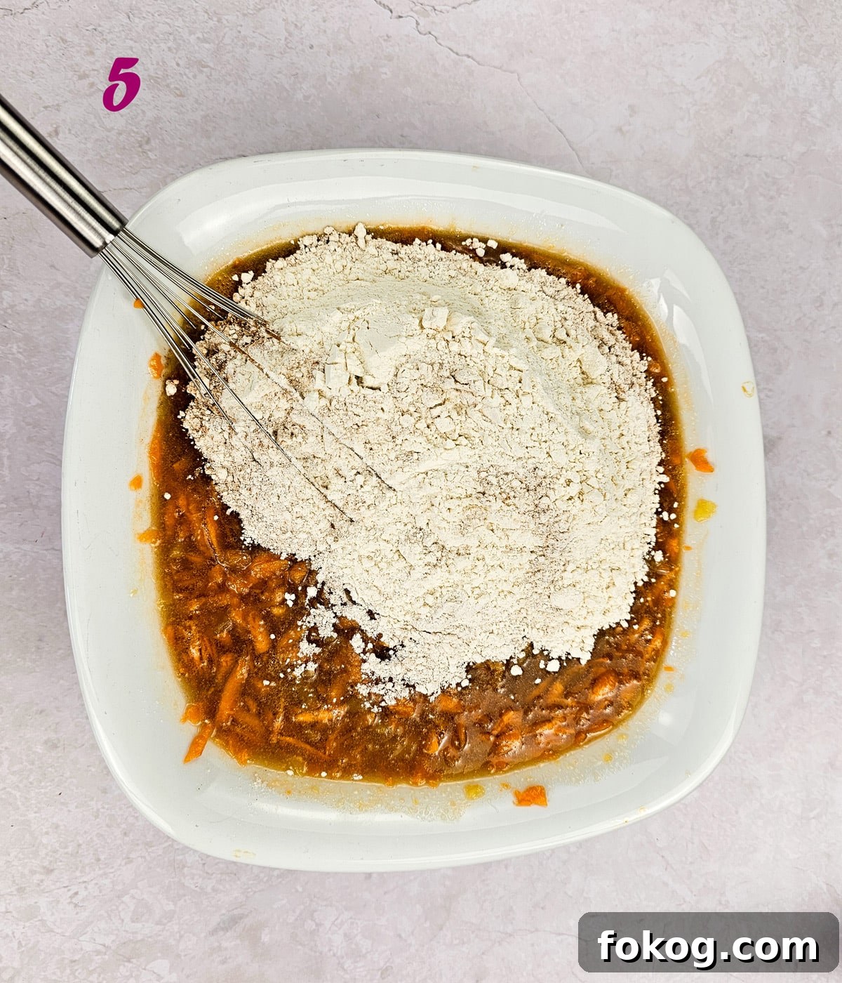 Flour and dry ingredients added to wet ingredients to make the best carrot cake.