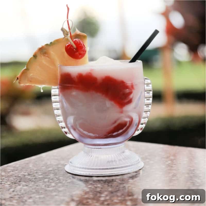 24+ Tropical Pineapple Juice Cocktail Recipes 16 red and white lava flow cocktail in a tiki glass with pineapple wedge and cherry garnish