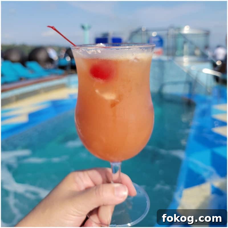 24+ Tropical Pineapple Juice Cocktail Recipes 17 pink orange cocktail in a hurricane glass with a cherry in front of a pool