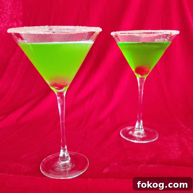 24+ Tropical Pineapple Juice Cocktail Recipes 6 Two Bright green cocktails with cherries in them in martini glasses with a sugared rim.