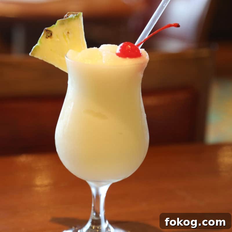 24+ Tropical Pineapple Juice Cocktail Recipes 7 Pina Colada in a hurricane glass with pineapple and cherry garnish