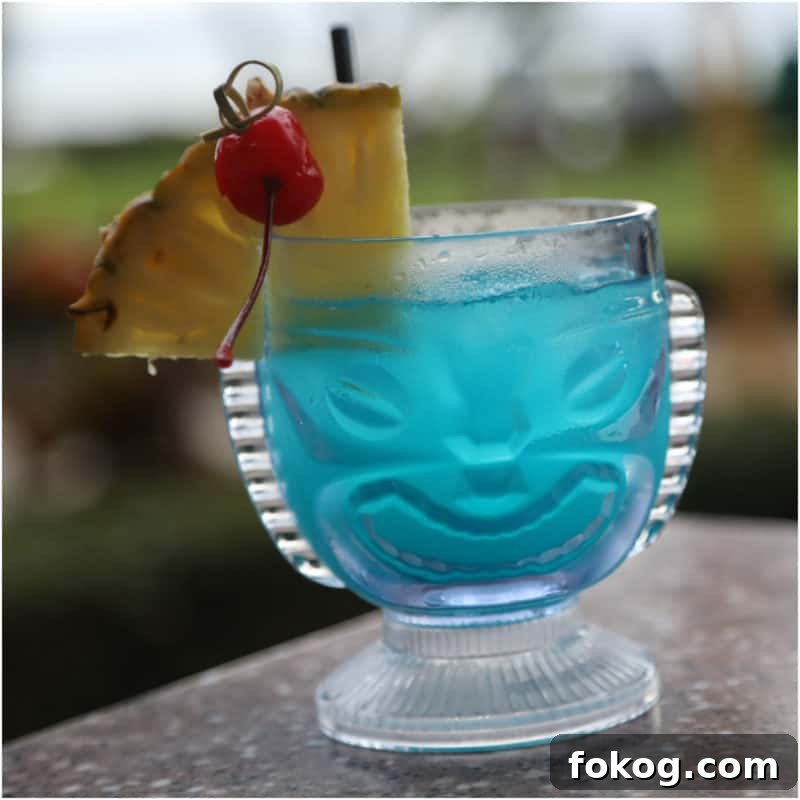 24+ Tropical Pineapple Juice Cocktail Recipes 9 Blue Hawaiian Cocktail in a tiki glass with pineapple wedge and cherry garnish
