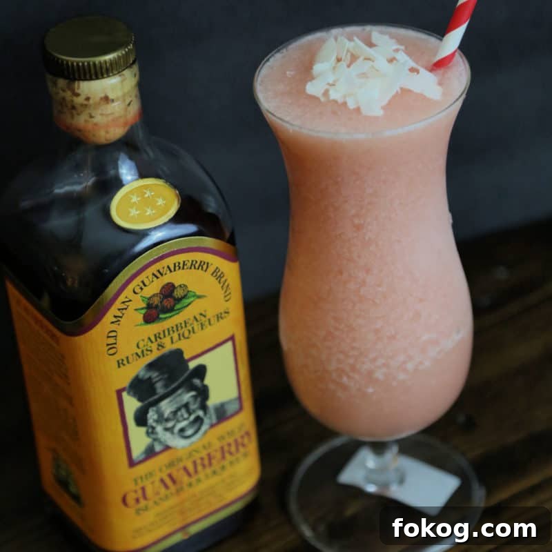 24+ Tropical Pineapple Juice Cocktail Recipes 10 Guavaberry Colada in a hurricane glass next to a bottle of Guavaberry