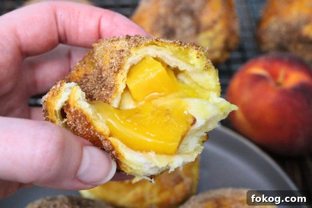 Air Fryer Peach Pie Biscuit Bombs - Quick Dessert 3 holding up half of a peach pie biscuit bomb to show the insides