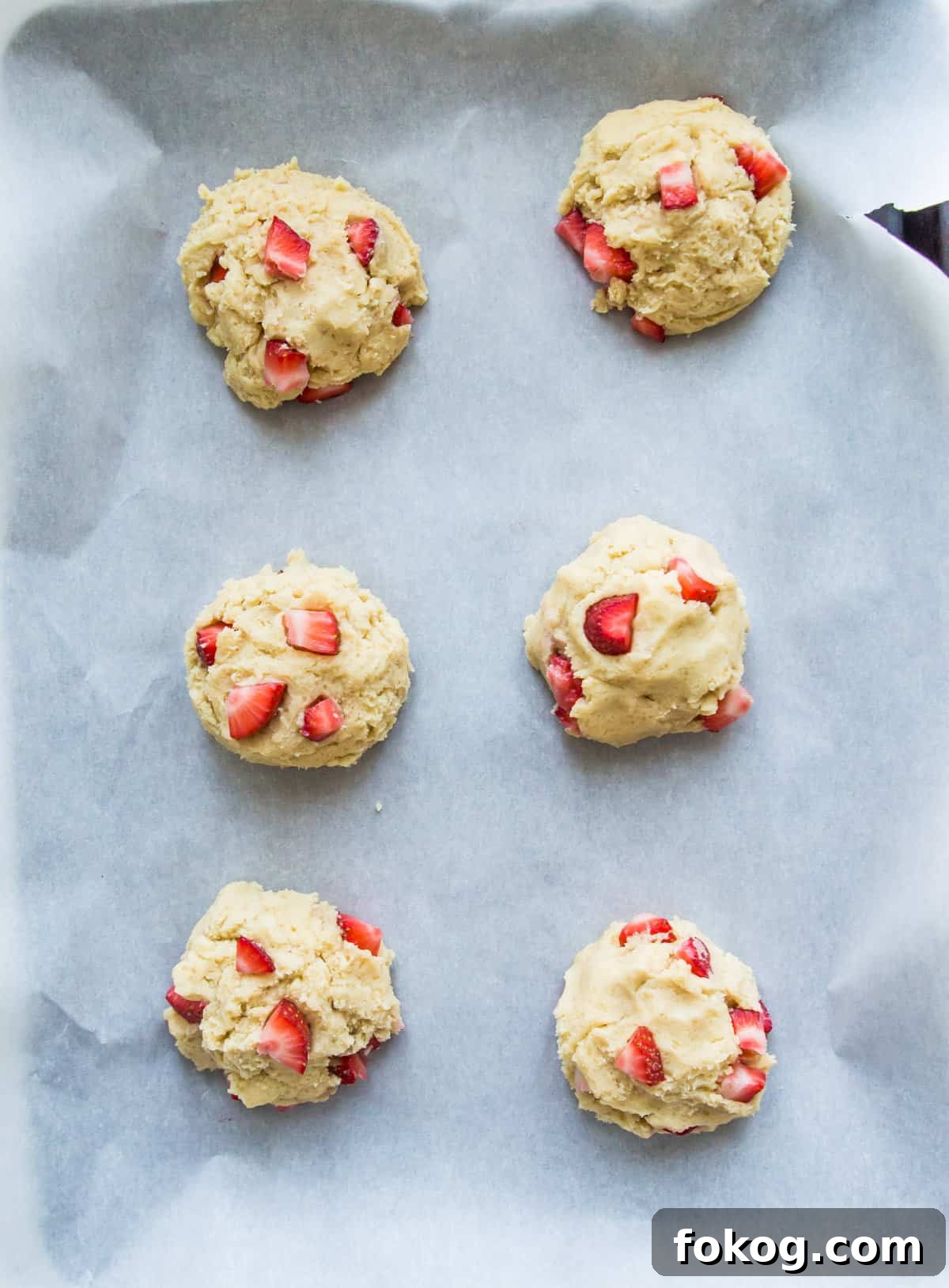 A baking sheet with strawberry cookie dough balls on it.