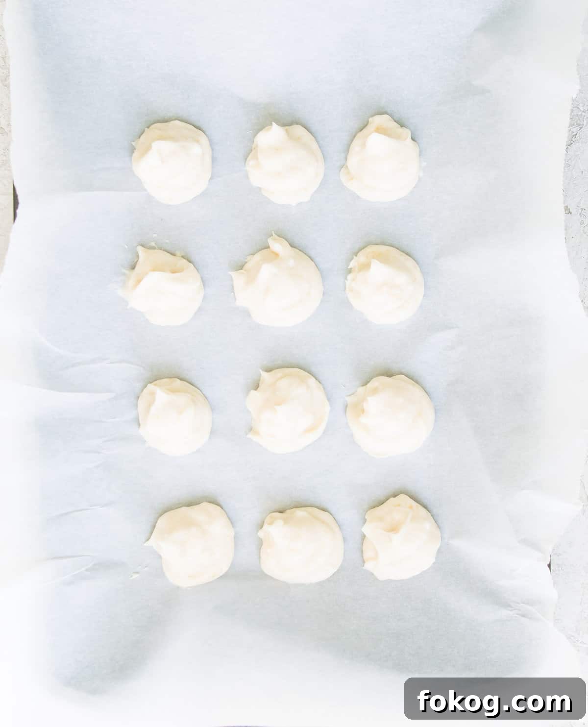 A piece of parchment paper with cream cheese balls on it.