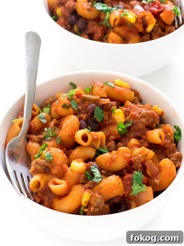 Two white bowls of mexican pasta with a fork.