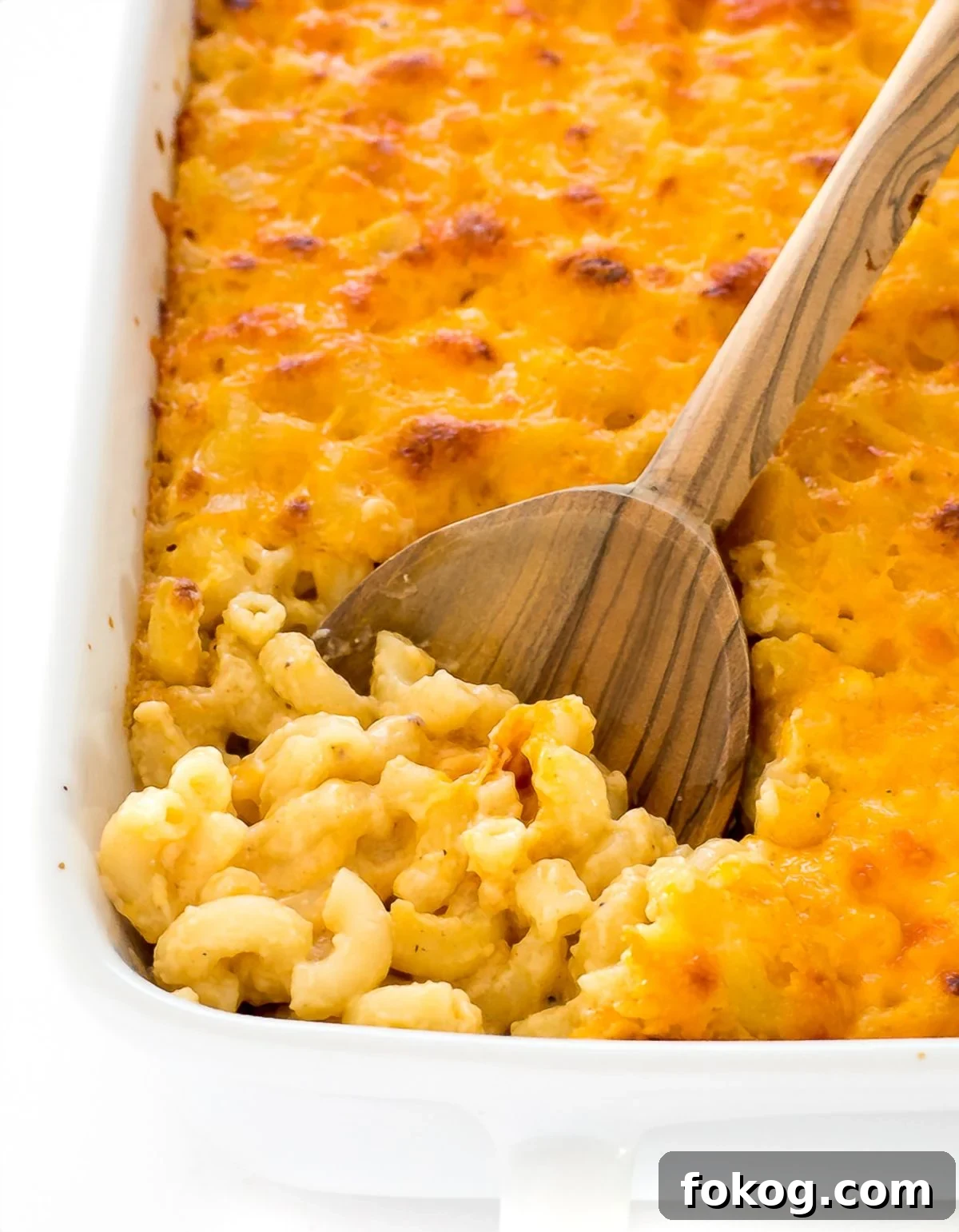 Macaroni and cheese in a white baking pan with wooden spoon. 