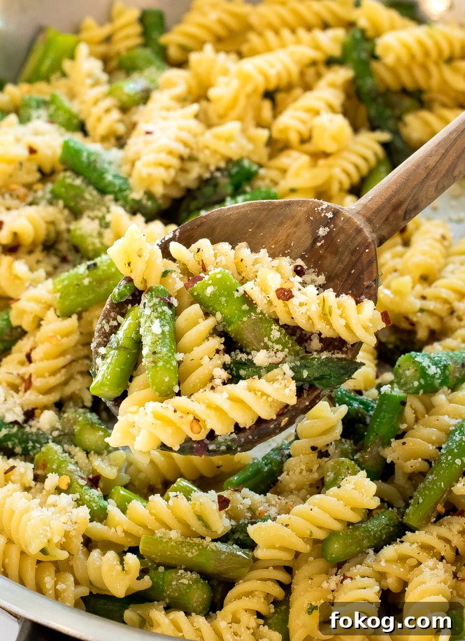 Upclose shot of noodles with asparagus in a silver pan. 