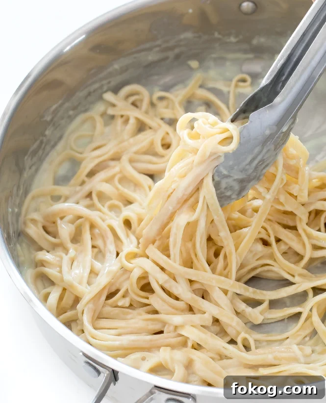 skinny lightened up fettuccini Alfredo in large skillet with tongs
