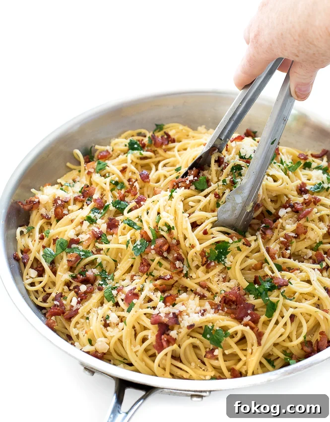 Spaghetti pasta with bacon and parmesan with tongs. 
