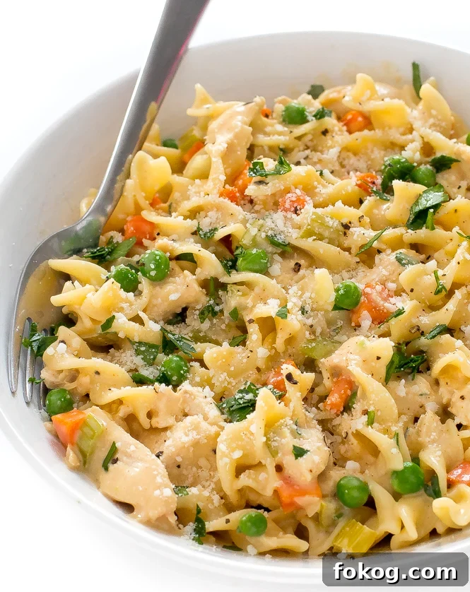 Pasta with peas and carrots in a white bowl with a fork. 