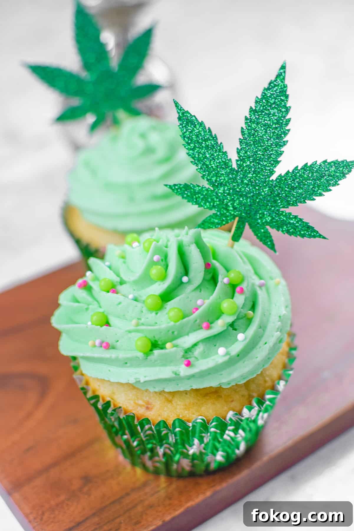How to Make Cannabis-Infused Cupcakes from Cake Mix 2 A white countertop with a cutting board and a cannabis cupcake topped with green frosting