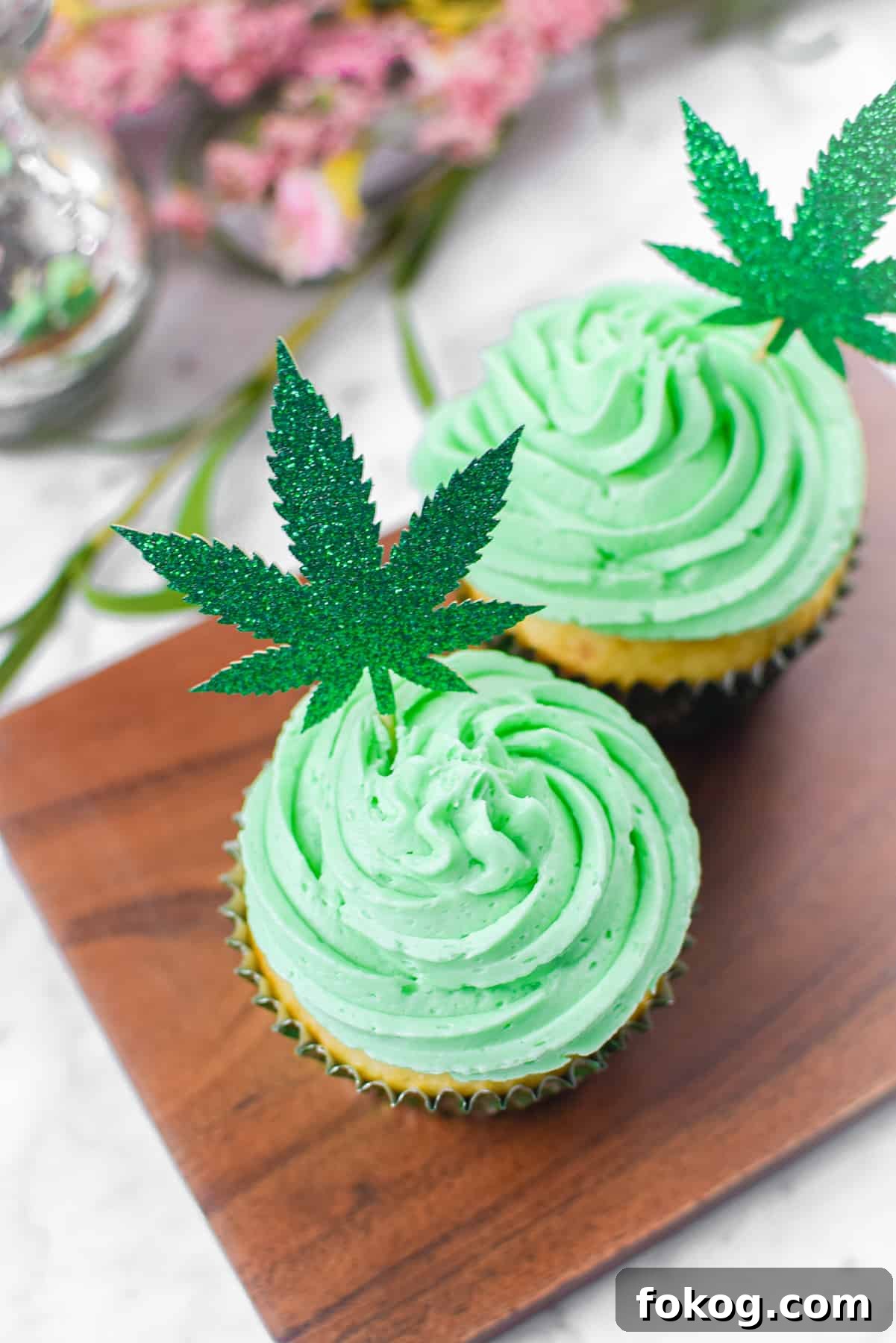 How to Make Cannabis-Infused Cupcakes from Cake Mix 11 A white countertop with a cutting board and a cannabis cupcake topped with green frosting