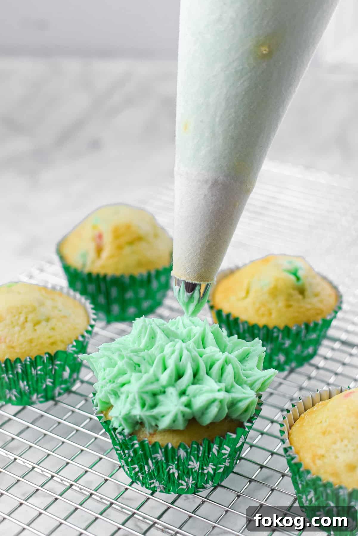 How to Make Cannabis-Infused Cupcakes from Cake Mix 10 A white countertop with a cutting board and a cannabis cupcake topped with green frosting