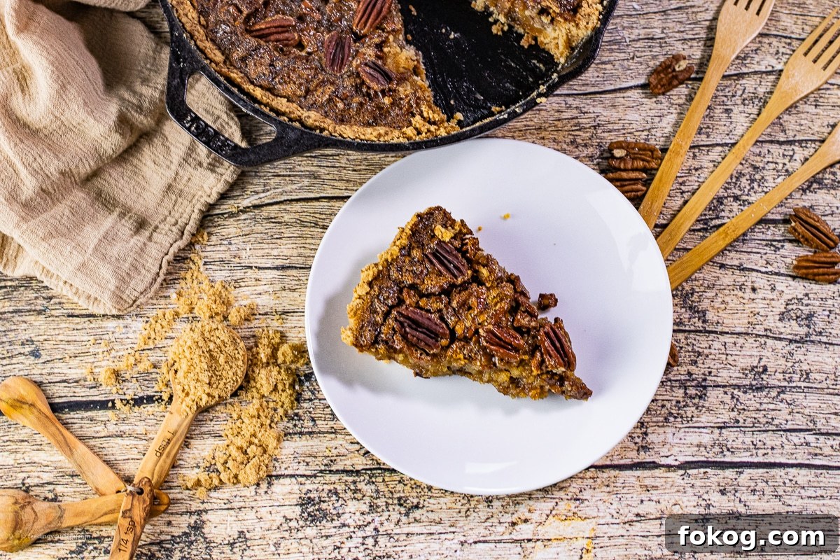 slice of pecan pie on a white plate cut from a skillet of pecan pie