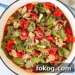 Ground chicken stir fry with veggies in a skillet with spoon on the bottom.