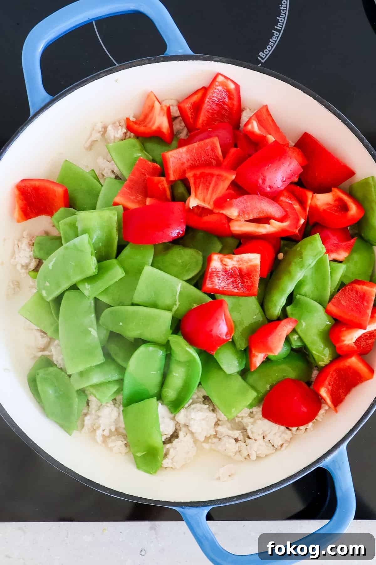 Snow peas and bell peppers added to the skillet.