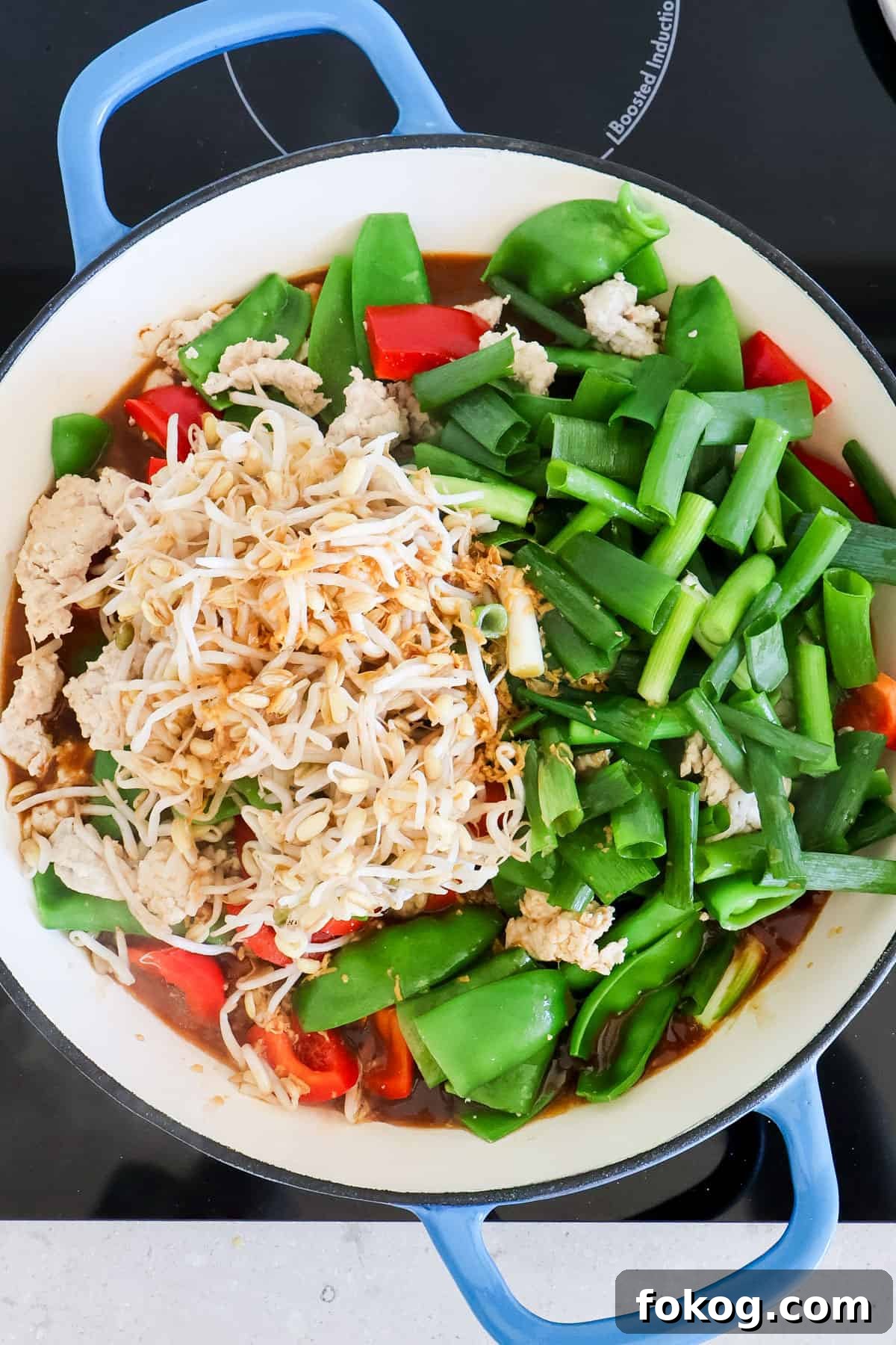 Bean sprouts, spring onion and sauce added to the skillet.