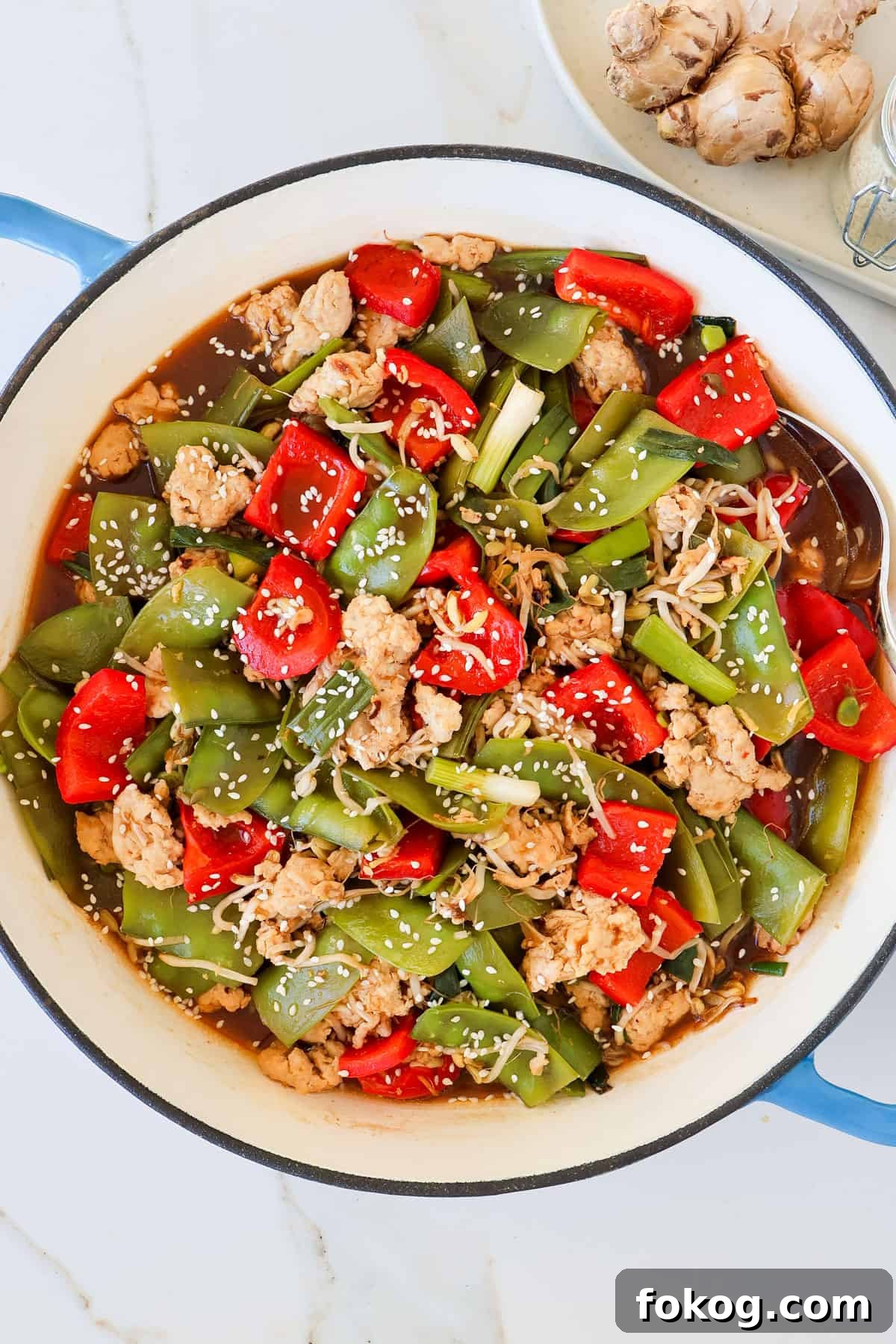 Ground chicken stir fry with veggies in a skillet.